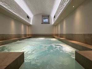 Un grand jacuzzi int érieur doté d’un plafond texturé et d’une petite fenêtre.