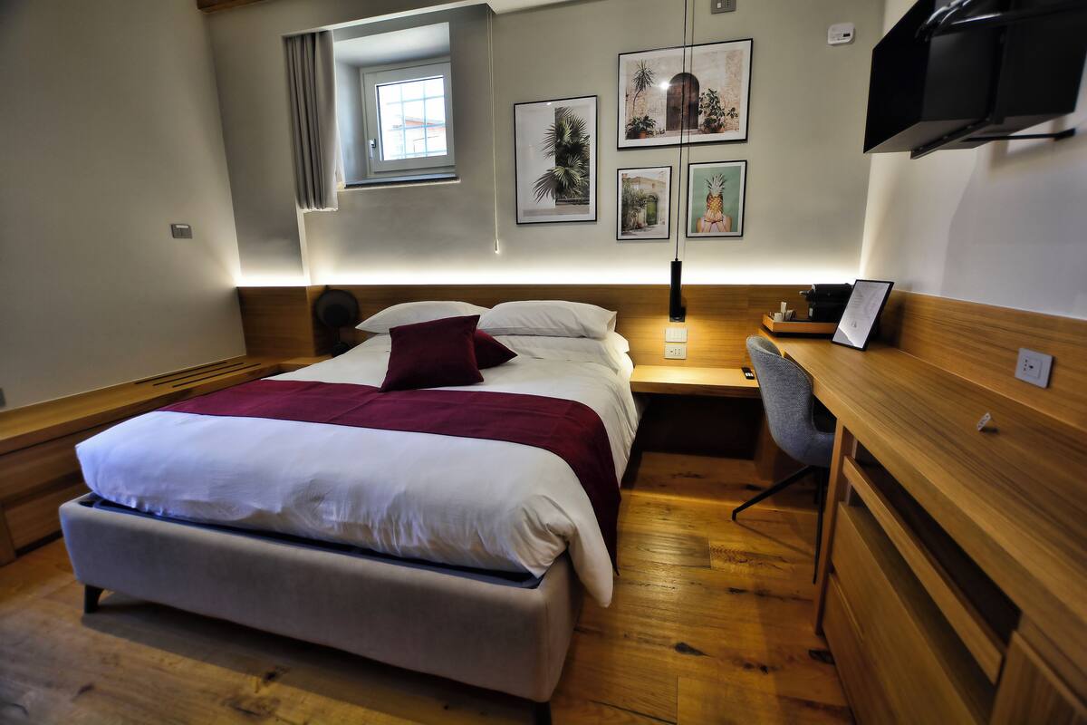 Un dormitorio ordenado con cama, mesita de noche y espacio de escritorio.