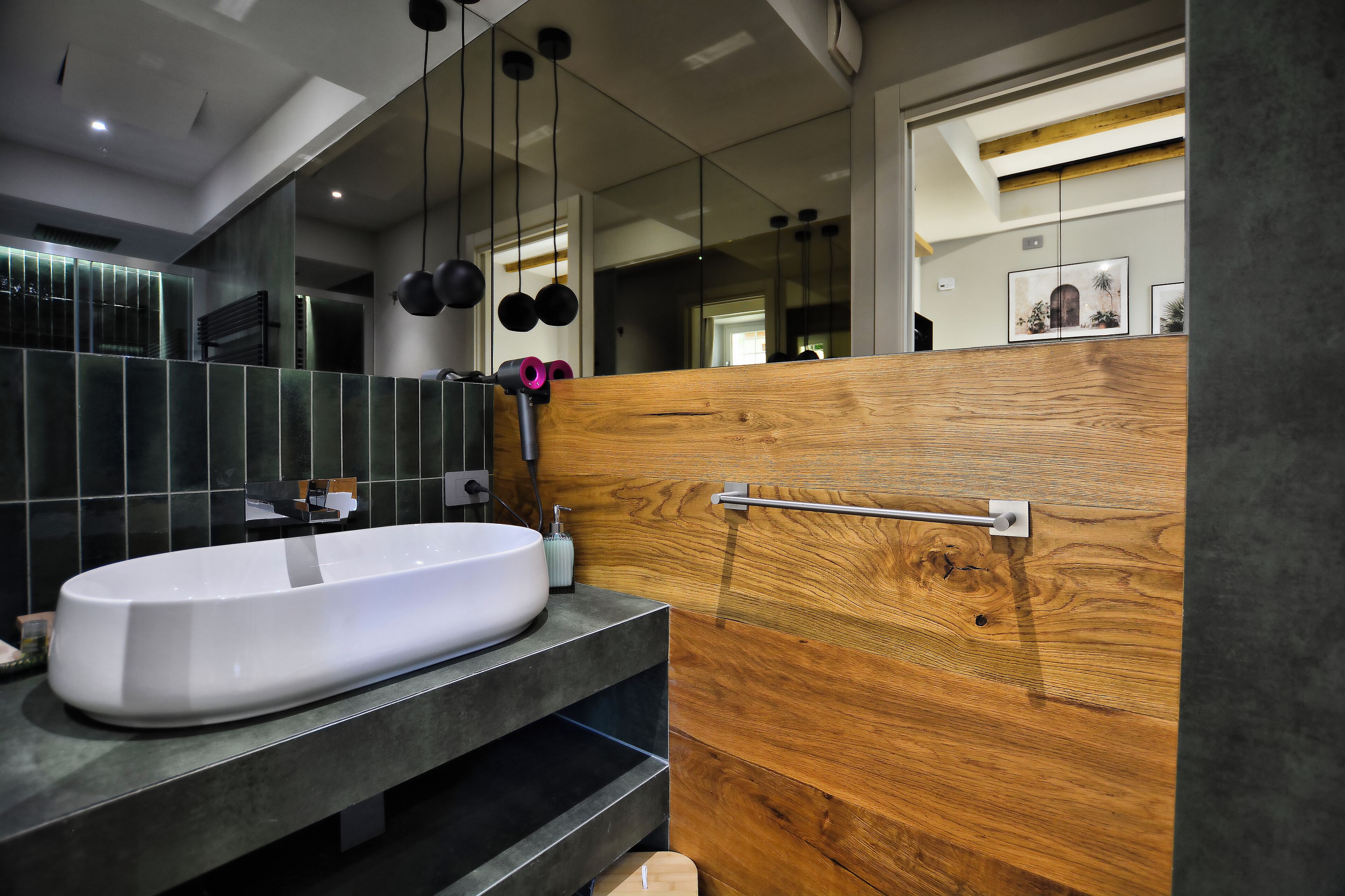 Un baño moderno con un lavabo grande de color blanco, baldosas oscuras y una pared decorativa de madera.