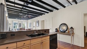 A kitchen with wooden cabinets, a dishwasher, and a black countertop. - Stay Next Door to City Market, Heated Pool Access (Savannah)