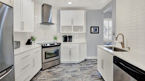 A modern kitchen with white cabinetry, stainless steel appliances, and a marble floor. - Walkable Home in Thomas Square, Heated Pool Access (Savannah)