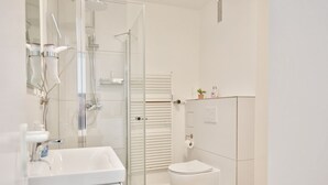 Une salle de bain moderne avec une douche à parois de verre, un lavabo blanc et des toilettes.