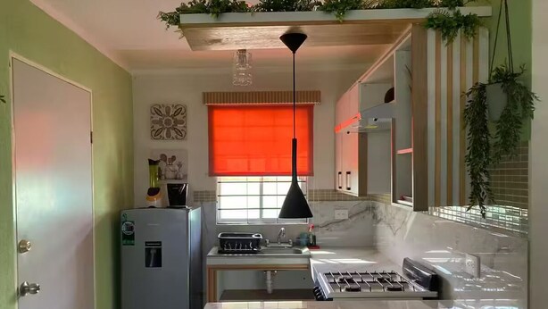 Una cocina compacta con refrigerador, estufa y lavaplatos.