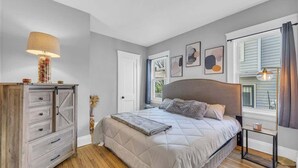 Une chambre à coucher avec un lit, une commode, une lampe et des œuvres d’art accrochées au mur.