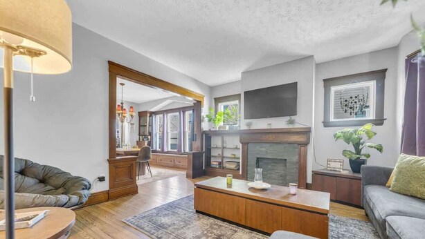 Un salon moderne avec une cheminée, des meubles en bois et un téléviseur fixé au mur.