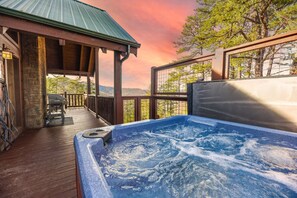 Un bain à remous sur une terrasse en bois, avec vue sur les arbres et les collines.
