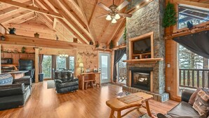 A spacious log cabin interior with a fireplace, wooden floors, and a dining area. - Big Blue Ridge | MTN Views, Hot Tub, Pool Table! (Sevierville)