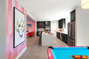 Una cocina moderna con armarios oscuros, una isla central y una mesa de billar.
