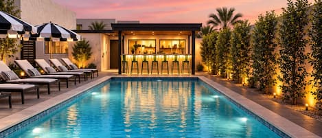 A swimming pool with lounge chairs and a bar area.