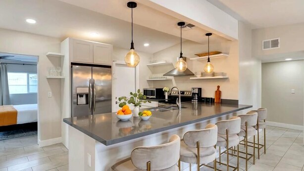 A modern kitchen with a central island, stainless steel appliances, and pendant lighting.