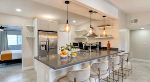 A modern kitchen with a central island, stainless steel appliances, and pendant lighting.