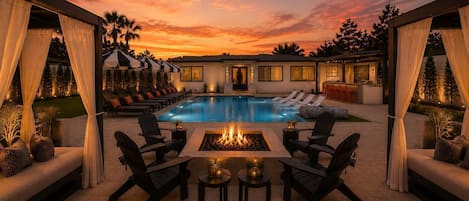 A poolside area with lounge chairs, a fire pit, and a bar area.