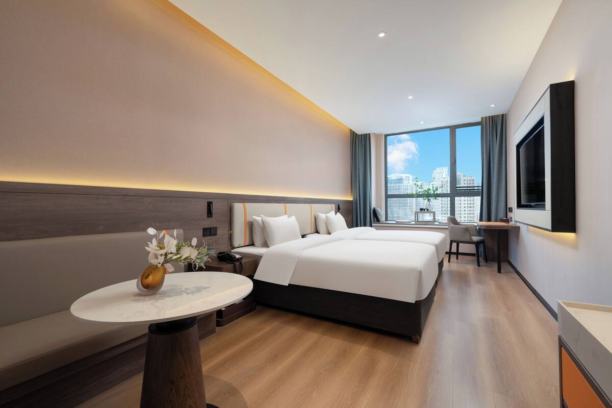 Ein modernes Hotelzimmer mit einem großen Bett, einem Schreibtisch und Blick auf die Stadt.