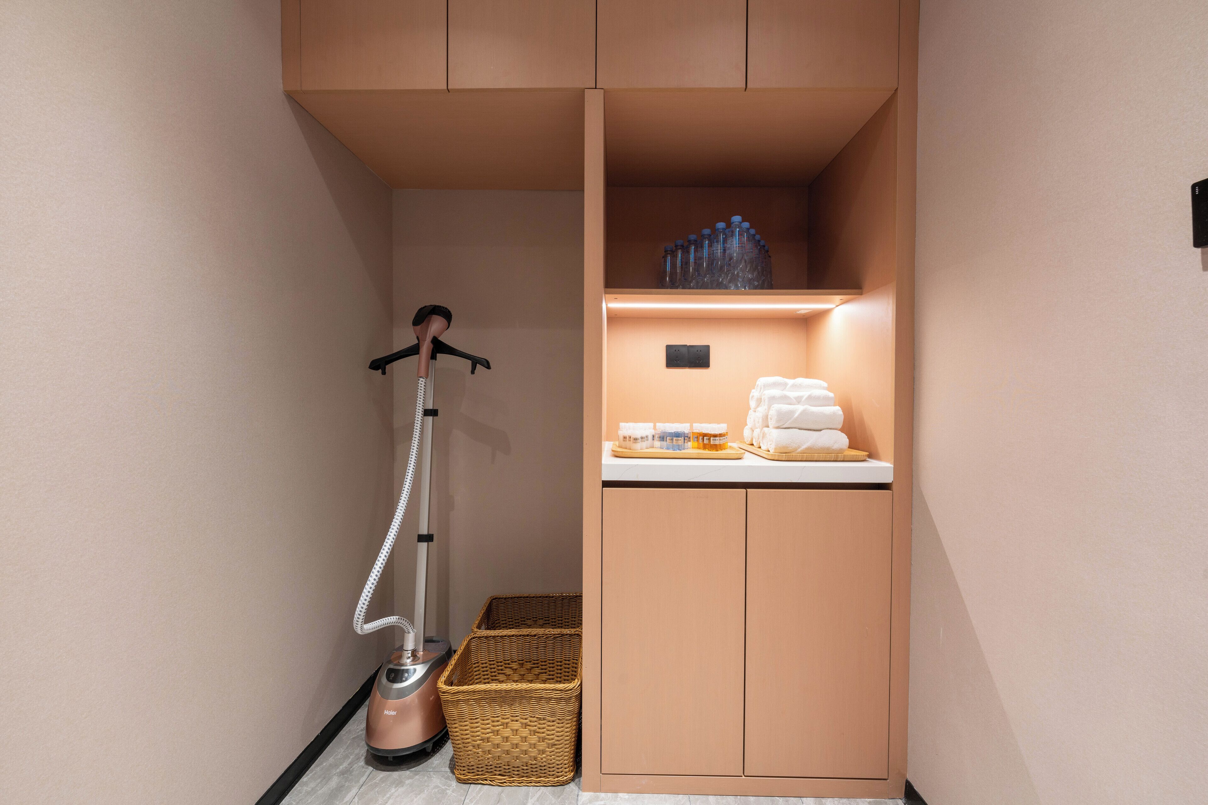 A compact bathroom with a built-in cabinet, a vacuum cleaner, and a basket.