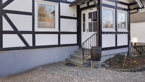 A building with a traditional half-timbered facade, a front door, and a small set of steps leading to the entrance.