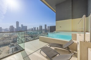A rooftop terrace with a swimming pool, lounge chairs, and a city view.