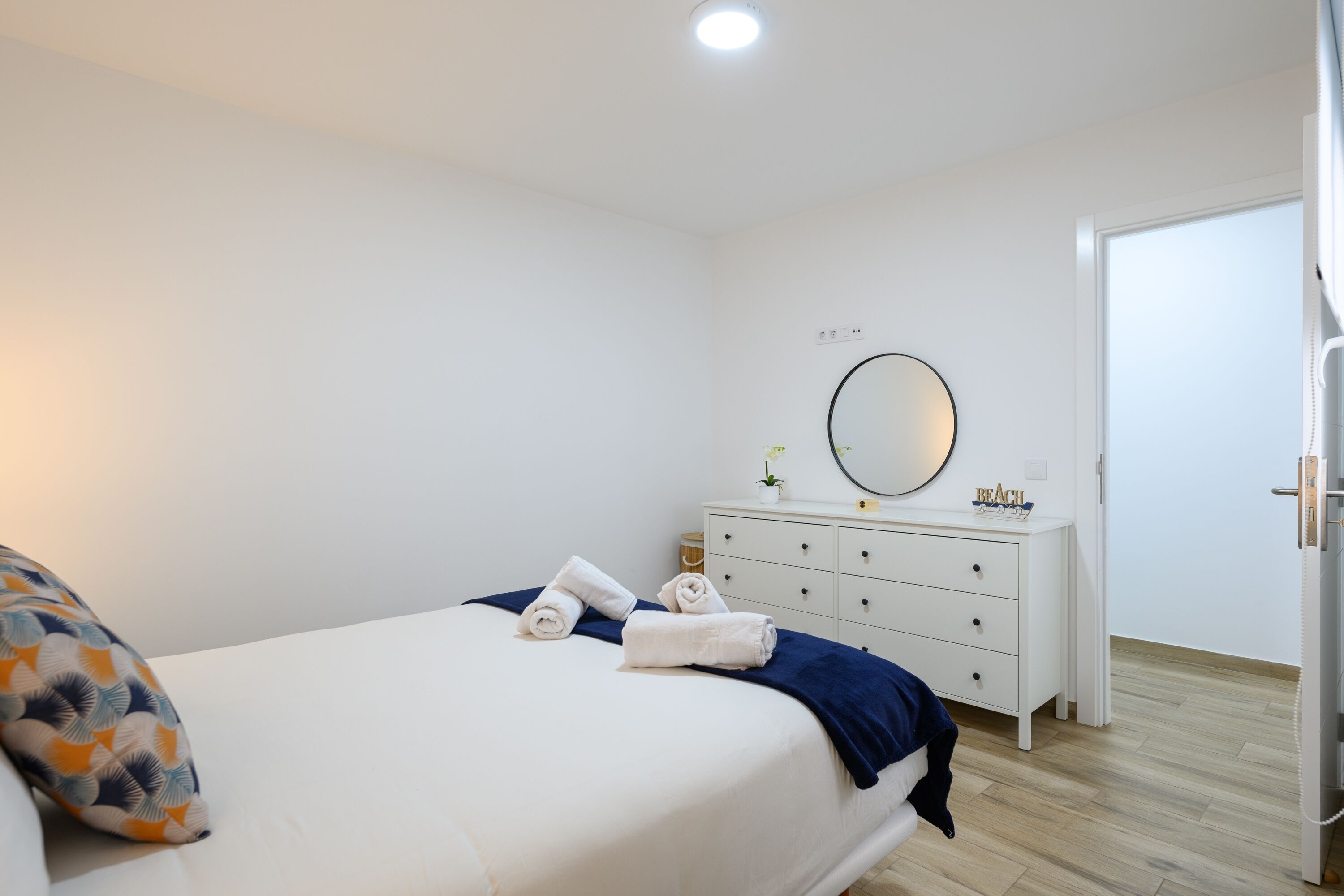 A bedroom with a bed, a dresser, a mirror, and a door.