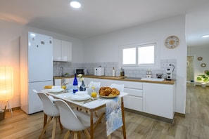 Een moderne keuken met witte kastjes, een eettafel gedekt met borden, glazen en een croissant.