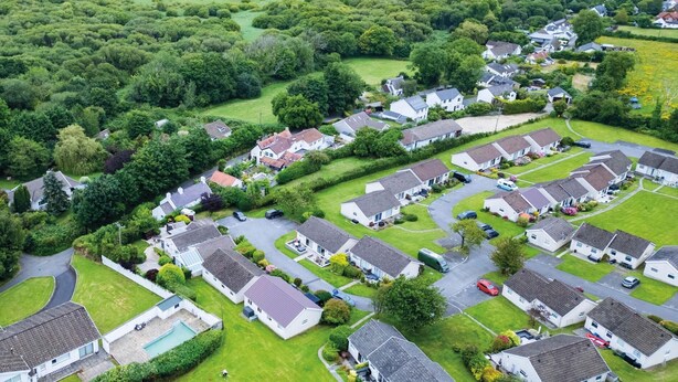 An aerial view of a residential area with houses, roads, and a coastline.