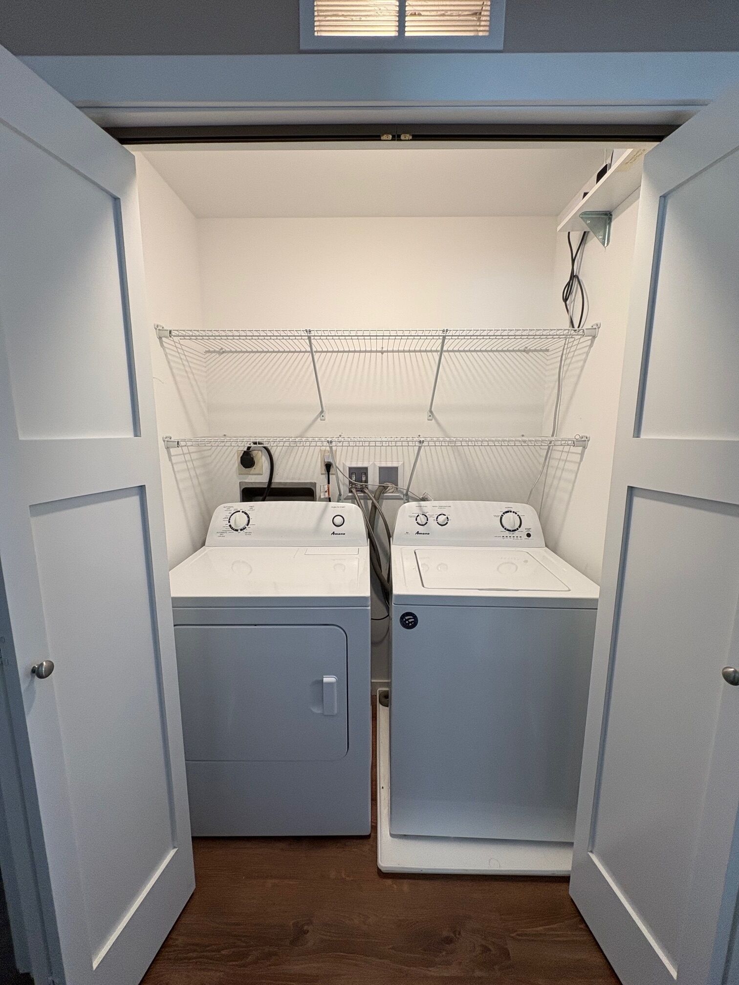 A laundry room with two washing machines and a drying rack.
