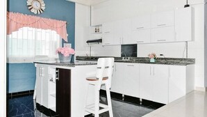 A modern kitchen with white cabinets, a black countertop, and a pink window valance. - House Hotel in San Andres Island (San Andrés)