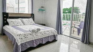 A bedroom with a bed, a nightstand, a wall-mounted shelf, and a view of the outside balcony. - House Hotel in San Andres Island (San Andrés)