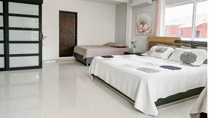 A modern bedroom with a large bed, a separate sofa bed, a wardrobe with glass doors, and a large window with a view of buildings. - House Hotel in San Andres Island (San Andrés)