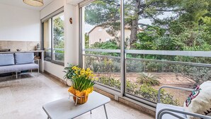 Ein modernes Zimmer mit einem großen Fenster, einem Sofa, einem kleinen Tisch mit einer Blumenvase und einer Hängelampe.