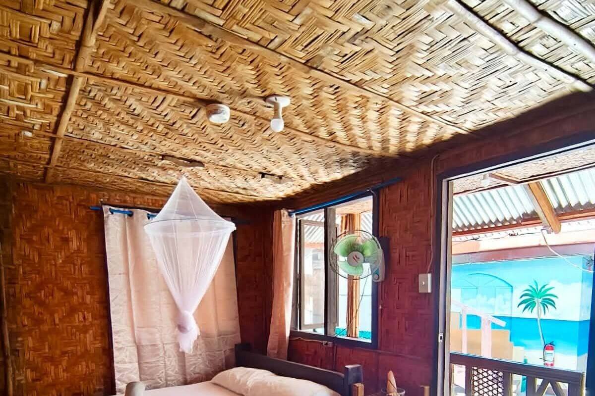 Una habitación con cama, ventilador, ventana y vista al exterior.