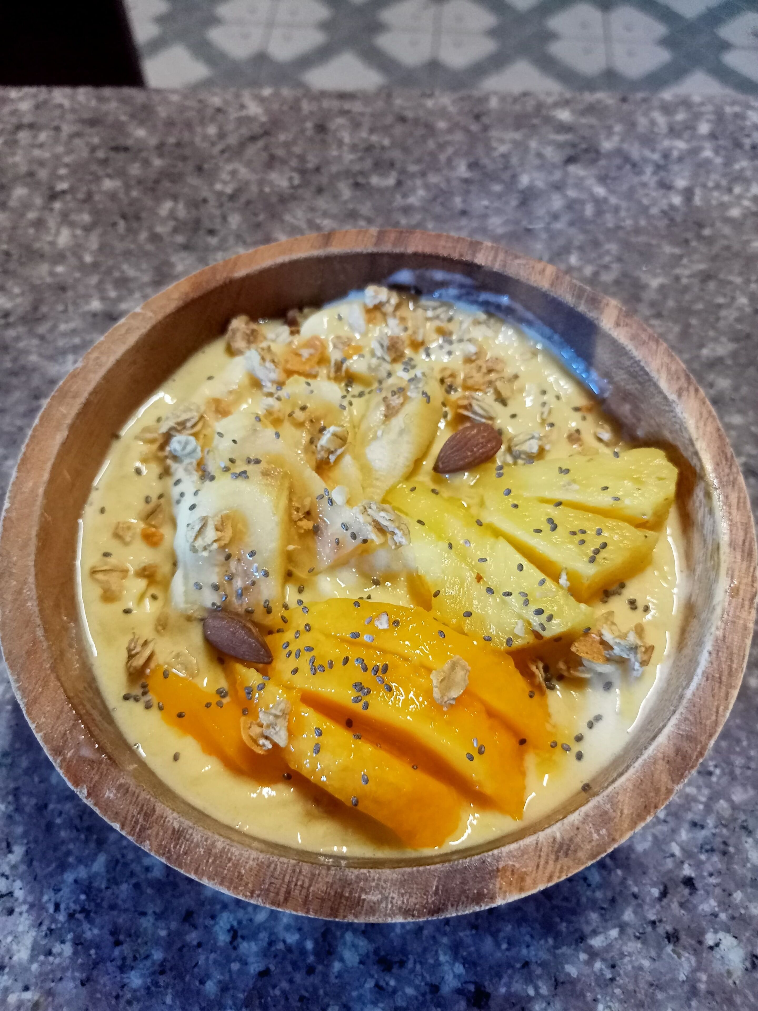 Een fruitsalade met noten en zaden op een granieten aanrecht.