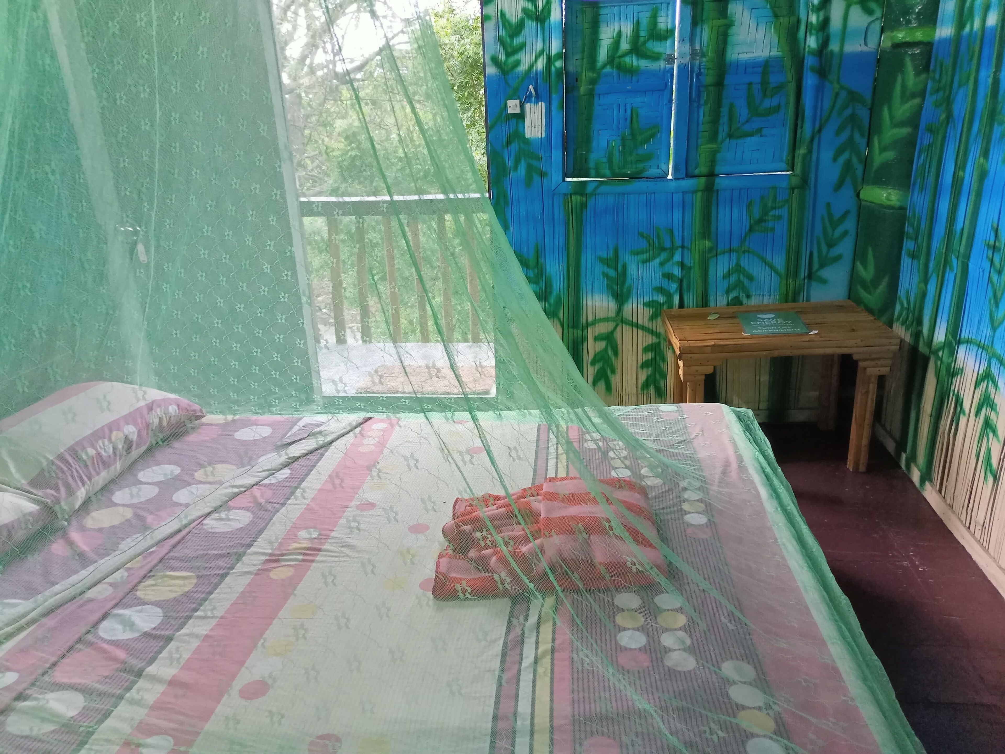 Une chambre avec un lit, une moustiquaire et une petite table.