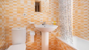 Een badkamer met een zwart-wit geruit betegelde vloer, een wit wastafelmeubel, een toilet en een douchegordijn.
