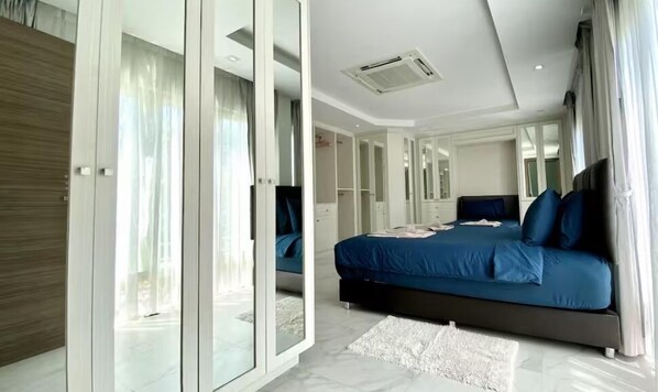 Une chambre moderne dotée d’un grand lit, d’armoires intégrées et d’une porte-fenêtre coulissante donnant sur un balcon.