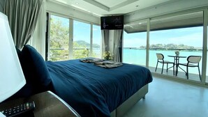 A bedroom with a large bed, a TV, and a balcony with a table and chairs. - Baan Jayden Duplex Seaview Villa (Phuket)