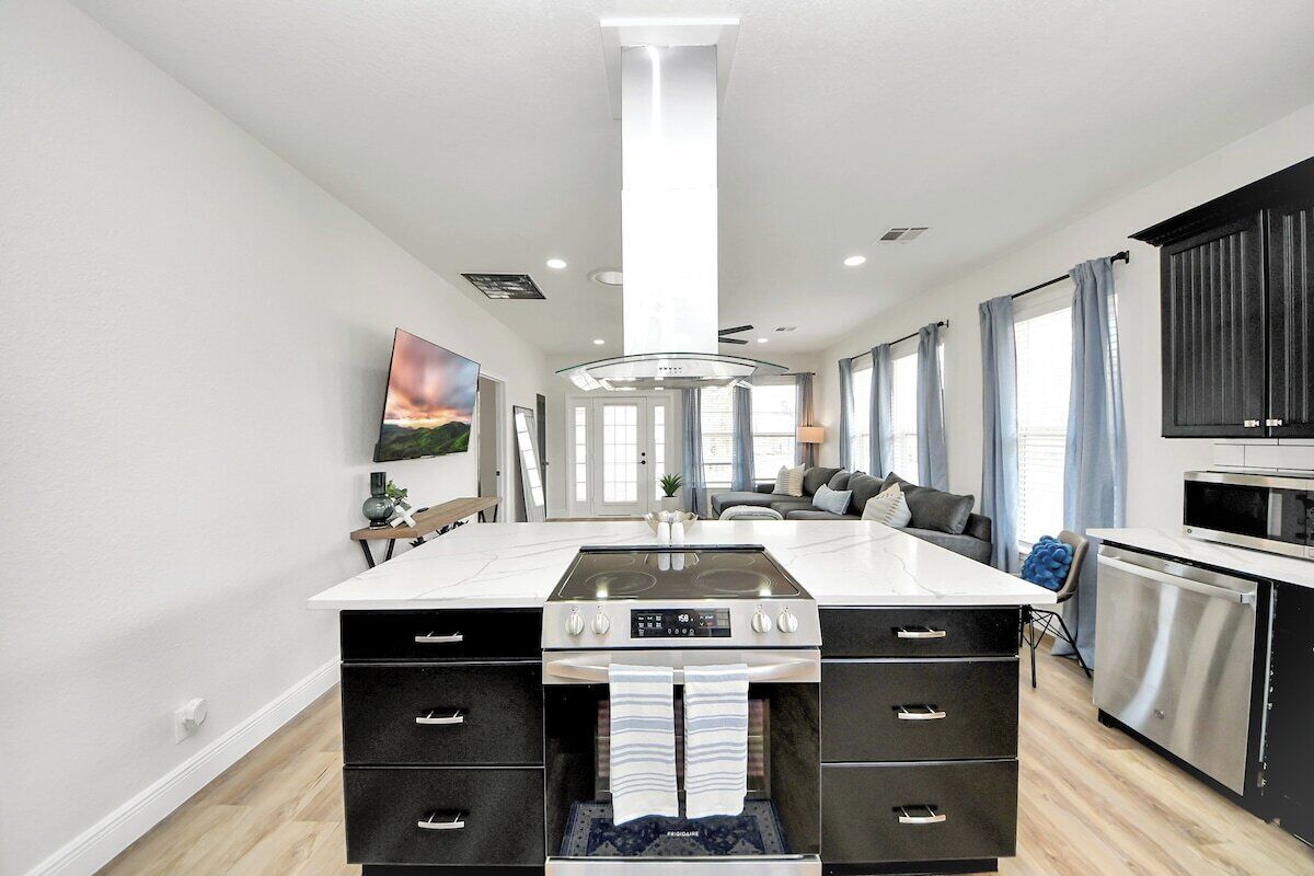 A modern kitchen with a central island, built-in oven, and stainless steel appliances.