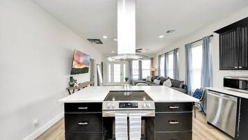 A modern kitchen with a central island, built-in oven, and stainless steel appliances.