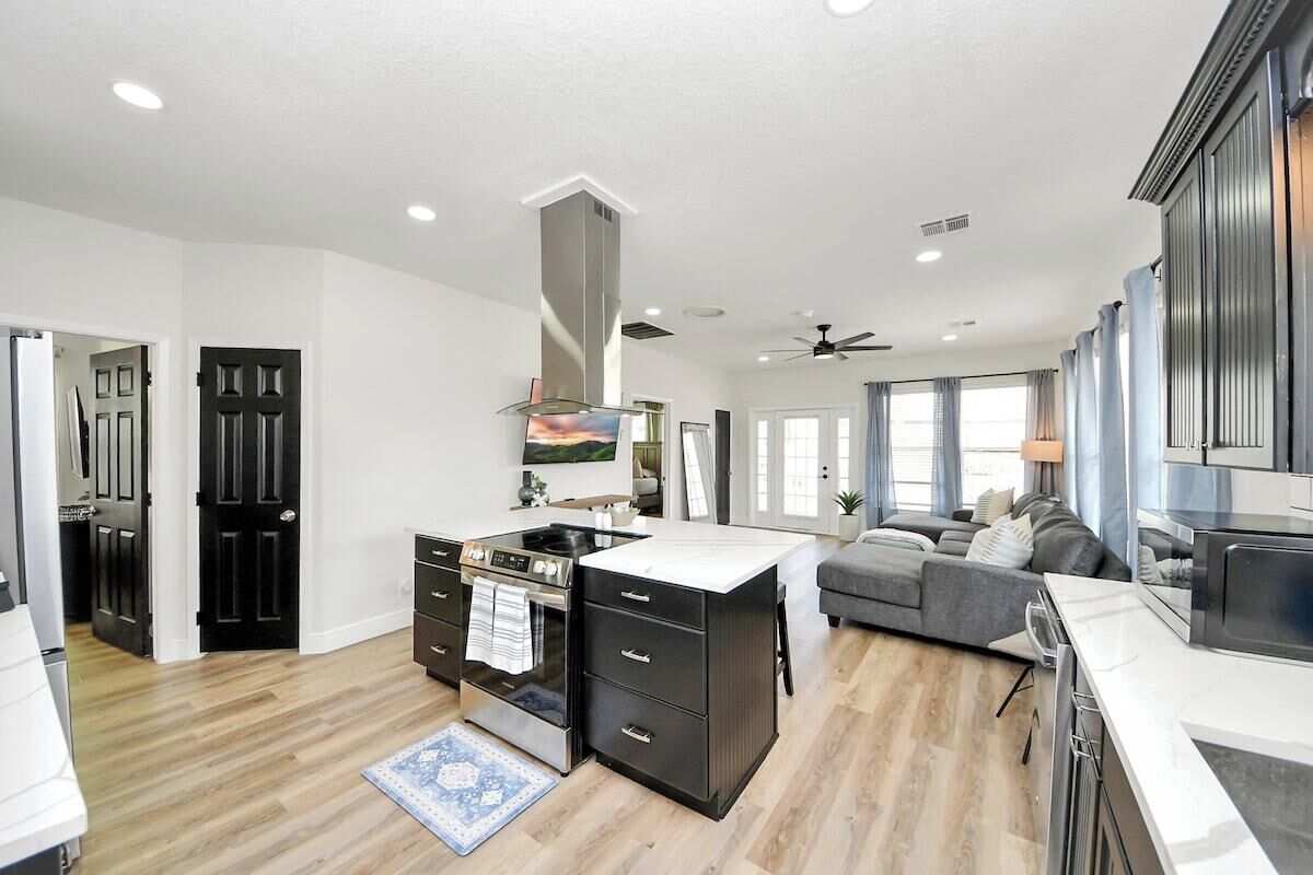 A spacious kitchen with a central island, a dining area with a sofa, and a living room with a TV.