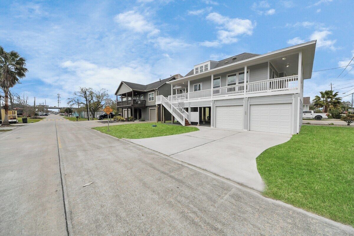 A two-story residential building with a front garage, a covered porch, and a staircase leading to the upper level.