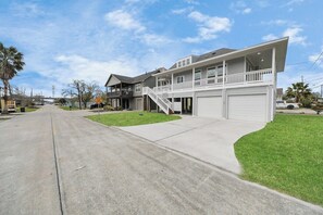 A two-story residential building with a front garage, a covered porch, and a staircase leading to the upper level.