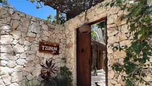 Un muro de piedra con una puerta de madera y un letrero que dice "TZUNUM jade".