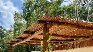 Un espacio exterior cubierto con piscina, una mesa y una persona trabajando en un portátil.