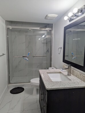 A modern bathroom with a glass-enclosed shower, a white sink, and a large mirror. - Queen bed occupancy with attached washroom - Close to YKF airport (Kitchener)