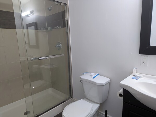 A bathroom with a glass-enclosed shower, a white toilet, and a sink. - Queen bed occupancy with attached washroom - Close to YKF airport (Kitchener)