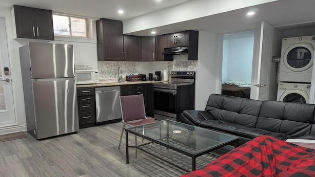 A compact kitchen with modern appliances, a dining area with a glass table, and a sofa.
