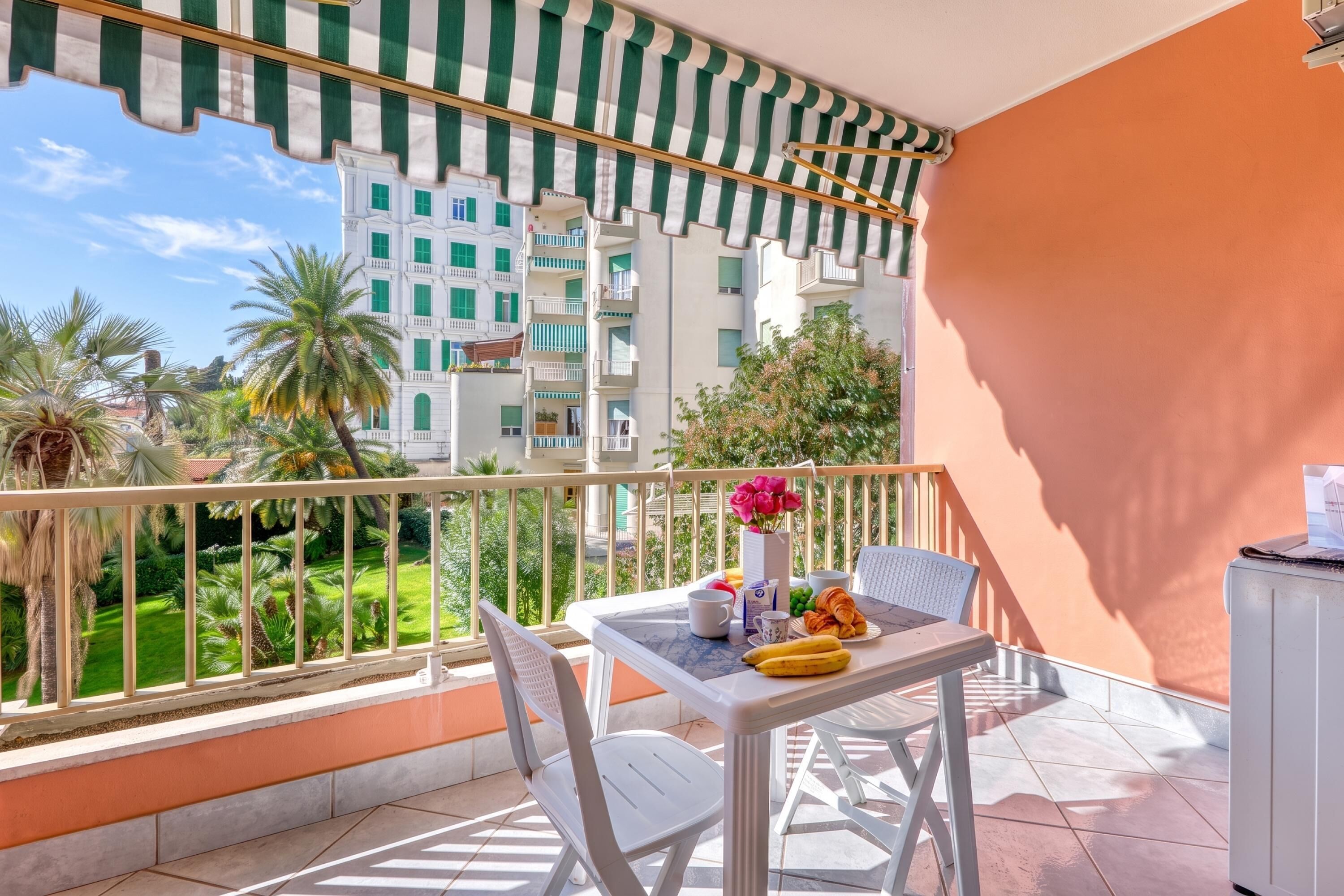 A balcony with a table set for breakfast, including croissants, bananas, and a cup.