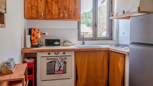 A compact kitchen with wooden cabinets, a built-in oven, a sink, and a window providing natural light.