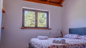 A bedroom with a bed, a window, and a desk.