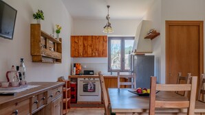 A compact kitchen with wooden cabinets, a built-in oven, and a dining area with a wooden table and chairs.