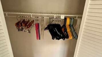 A walk-in closet with a wooden floor, white walls, and a white ceiling.