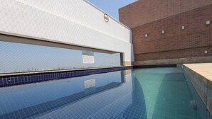 Ein Schwimmbecken mit gefliestem Rand, einer weißen Wand und einer Backsteinwand im Hintergrund.